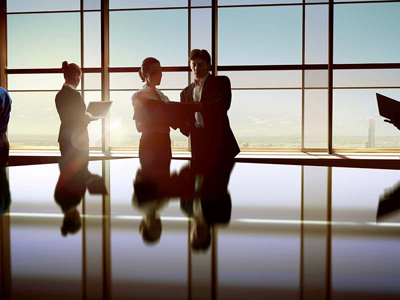 professionals having a discussion by a window.